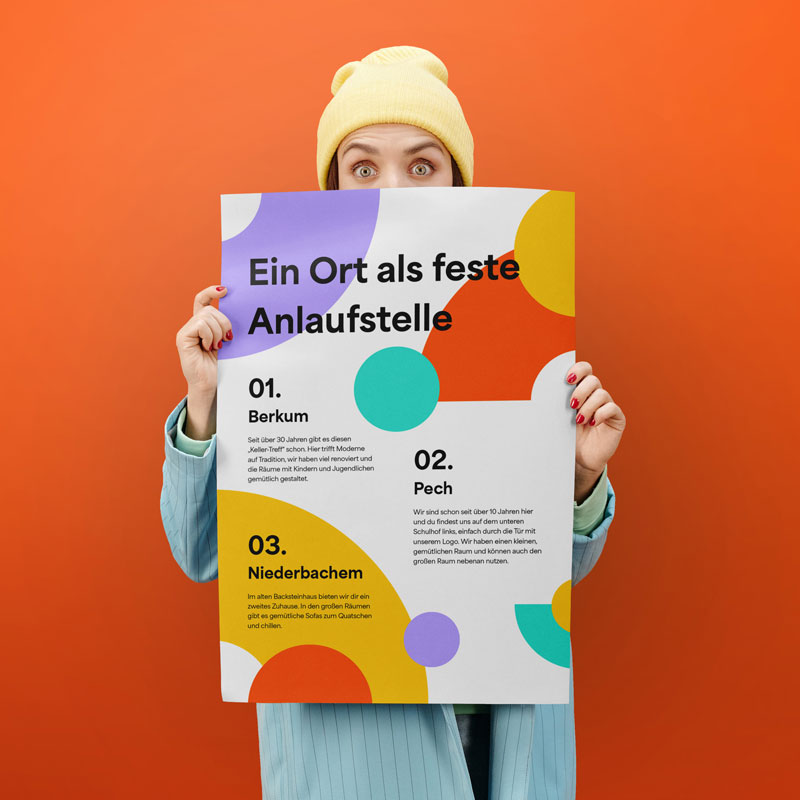 Mockup eines Plakats, das von einer weiblichen Person gehalten wird. Das Motiv zeigt ein Plakat des Jugendzentrums Wachtberg mit dem Titel "Ein Ort als feste Anlaufstelle"